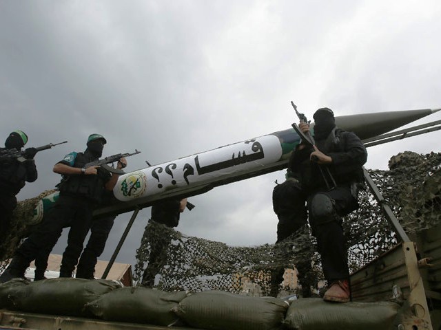 Palestinian members of al-Qassam Brigade display a home-made Qassam rocket during military parade on 27th anniversary of Hamas, Gaza