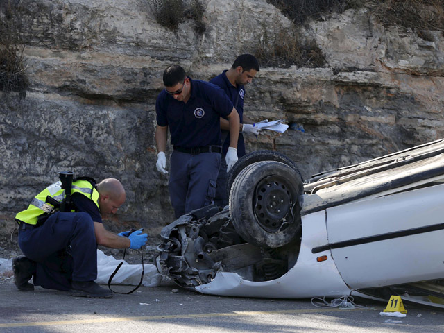 Israeli policemen inspect overturned car following ramming attack near Shiloh