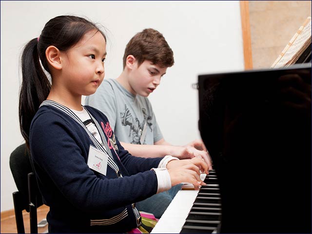 Chinese and Israeli children playing piano together at the Chinese-Israel Joint Master Class for Outstanding Young Pianists at the Jerusalem Music Center