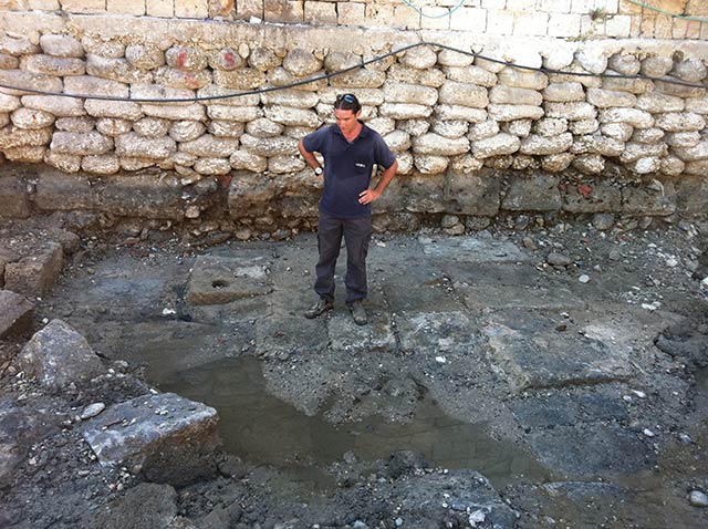 Member of the IAA Marine Archaeology Unit standing on the ancient quay that was exposed in Akko