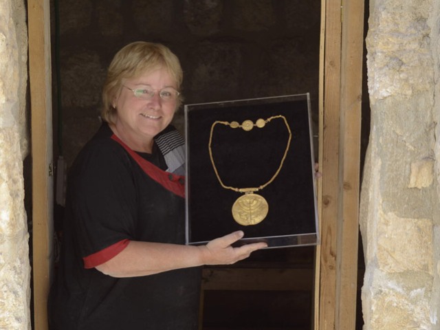 Dr. Eilat Mazar displays a 10-cm gold medallion etched with menorah, shofar and Torah scroll