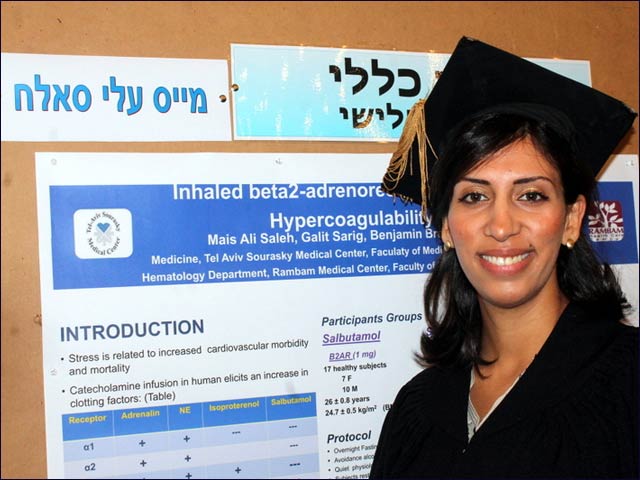 Mais Ali Saleh on graduation day, posing beside her student research project.