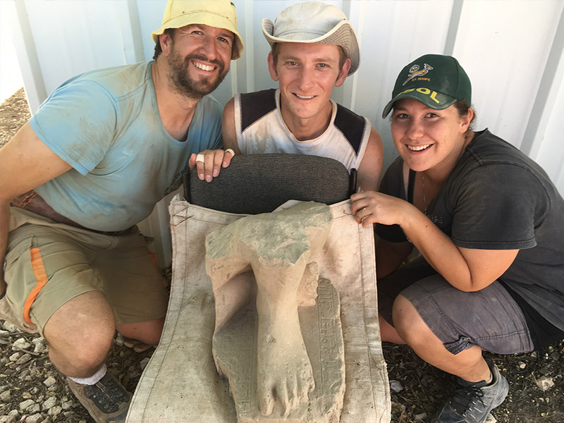 The statue with the three volunteer excavators who found it, from left: Valentin Sama-Rojo, Bryan Kovach and Elanji Swart.