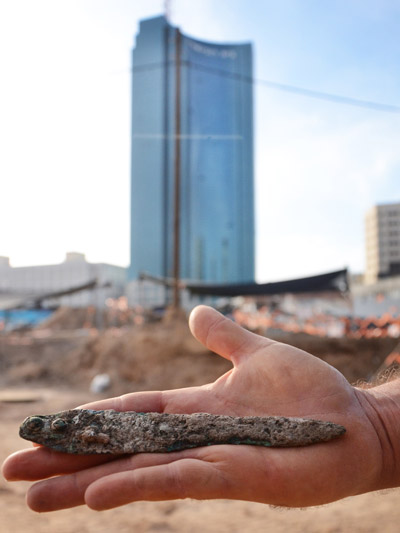 Bronze dagger against the backdrop of the excavation and the towers