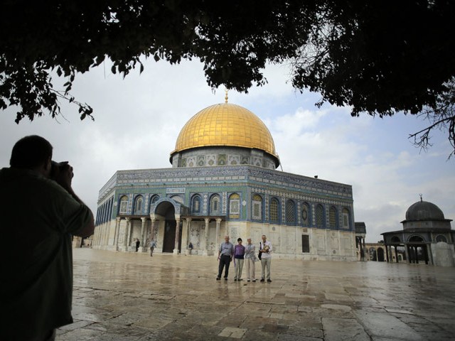 Tourists pose for a picture in front of the Dome of the Rock on the Temple Mount compound