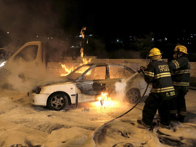 Firefighters douse a burning car with foam after it was hit by a petrol bomb in Jerusalem (Aug 3, 2015) injuring two Israelis