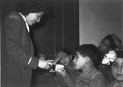 Israeli stewardness at Lod Airport giving a drink to young immigrant from Morocco, Nov 1949