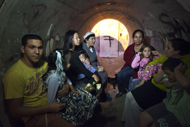 Israelis take cover inside a sewage pipe used as shelter during alert warning of incoming rockets