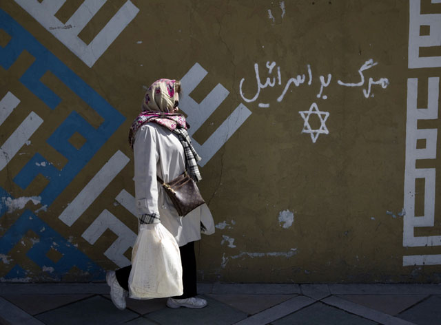 Woman walks past writing on a wall in Persian that reads, "Down with Israel", in northern Tehran - March 2012