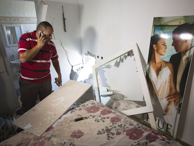 Avihai Jorno inspects the damage to his home in Sderot hit by a rocket fired from Gaza