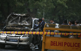 Police and forensic officials examine a damaged Israeli embassy car after an explosion in New Delhi