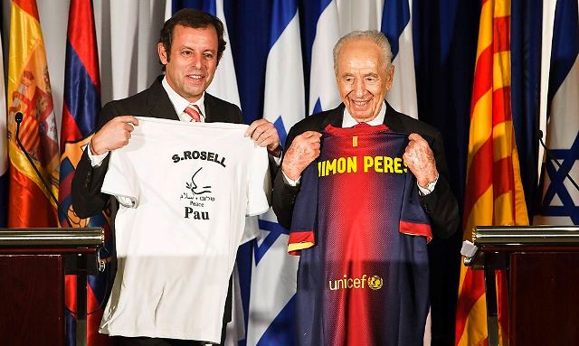 Israel's President Shimon Peres (R) and President of Barcelona soccer team Sandro Rosell hold t-shirts which they gave one other as gifts during a news conference in Tel Aviv February 21, 2013. Rosell announced on Thursday that the Catalonian giants will